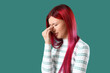 © Pixel-Shot - Young worried woman with bright hair color on green background