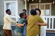 © Seventyfour - Waist up of happy African American family embracing outdoors welcoming guests for party