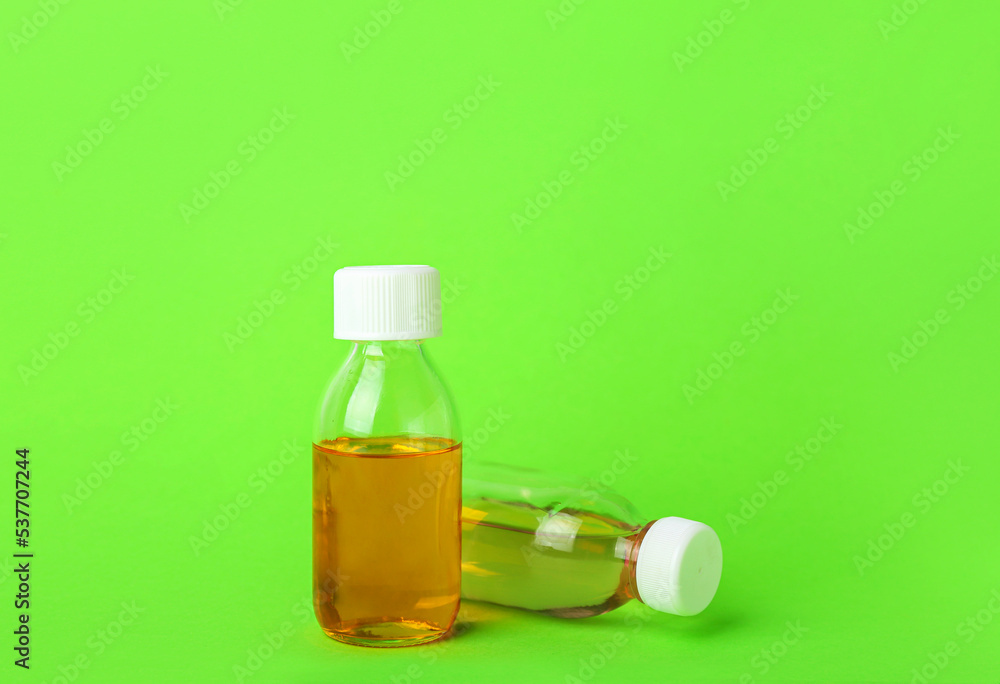 Bottles of cough syrup on green background