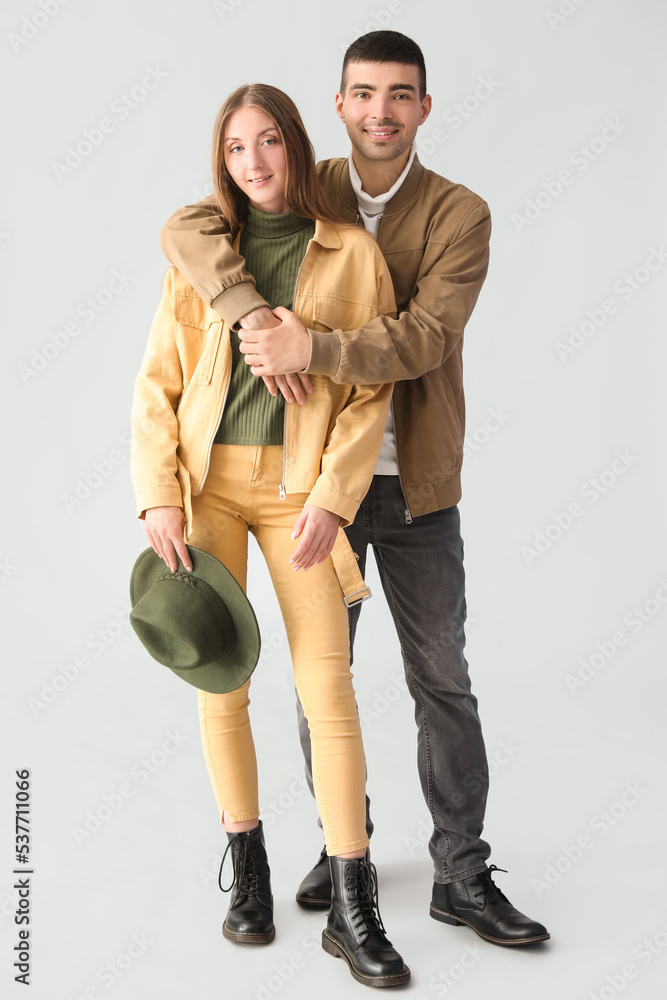 Fashionable young couple in autumn clothes on light background