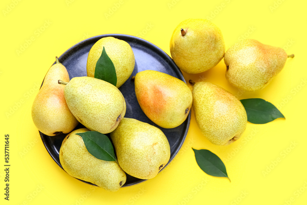 Plate with ripe pears on yellow background