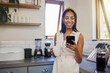 © Nina Lawrenson/peopleimages.com - Coffee break, smartphone and black woman in kitchen with mobile app notification, online networking or funny social media post in morning. Happy gen z girl using phone for website quote information