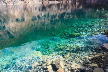 Wall Mural - Texture of emerald clear water and natural stones. Natural background. Blue Lake.
