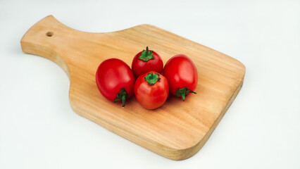 Pile of tomatoes on a wooden board. Ripe tomatoes with cut lines. Organic fresh tomatoes isolated on white.