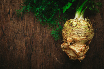 Root celery with green stems, rustic wooden kitchen table background, top view