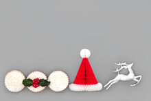 Christmas Festive Decorations And Symbols With Santa Party Hat, Reindeer And Mince Pie Food With Holly On Gray Background. Minimal Composition For Xmas And New Year Season.