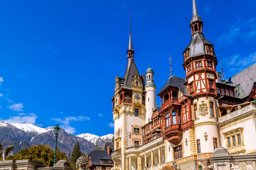 Peles castle tower close-up view and Carpathian mountains snow peaks, Sinaia, Transylvania, Romania