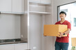 © Johnstocker - Young man carry large package walk into new house