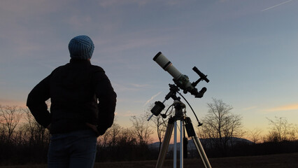 Wall Mural - silhouette of a man, telescope and countryside under evening skies.