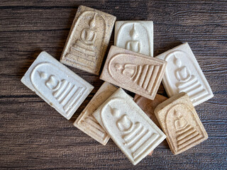 Thai buddha amulet isolated on wooden background.