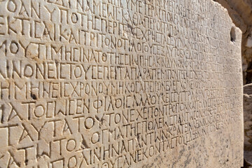 Fragment of ancient greek inscription, carved on marble block at the archaeological site of Ephesus. Selcuk, Turkey (Turkiye). Selected focus. Ancient art and history concept. Retro background