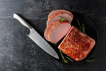 Wall Mural - Smoked ham and kitchen knife on a black stone table.