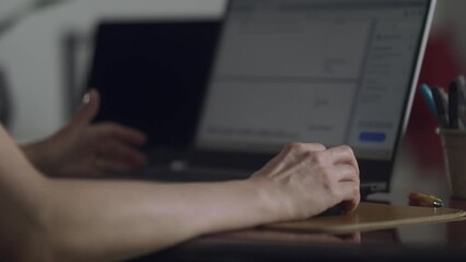 Static shot of unrecognizable woman working on her laptop, doing spreadsheets. 