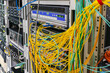 © Климов Максим - There is a rack with network equipment in the server room. There are a lot of messy wires on the server patch panel