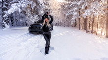 The Car Is In The Woods In Winter. A Girl In The Background Of A Car. Light Breaks Through The Trees