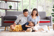 © aekkorn - Portrait of a happy young family. Mom; dad and daughter look at the camera and smile. The faces of Asian parents and their child in living room. Family funning in living room.
