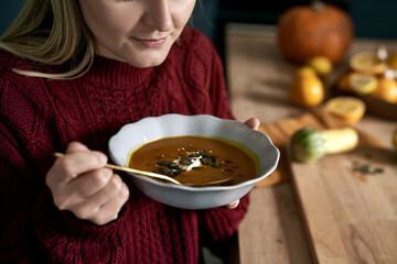 Close up of caucasian woman start eating warming pumpkin soup