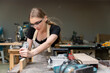© SKW - Portrait of a female carpenter using furniture tools in a furniture factory. she is using a planer planing with wood used to create furniture with modern tools