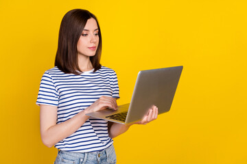 Poster - Photo portrait of lovely young lady hold netbook focused remote working hr wear stylish striped garment isolated on yellow color background