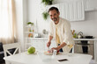 © LIGHTFIELD STUDIOS - bearded man smiling at camera while cutting cherry tomatoes near fresh lettuce.