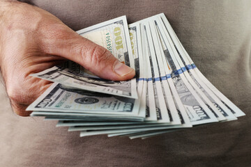 Wall Mural - A man holds a stack of hundred dollar bills in his hand. Close-up.