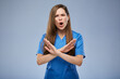 © Yuriy Shevtsov - Entering without protective medical equipment is forbidden. Woman in blue medical uniform makes stop symbol with crossed hands. Isolated female portrait.