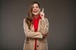 Young modern business woman in brown fall coat pointing finger. Advertising isolated portrait.