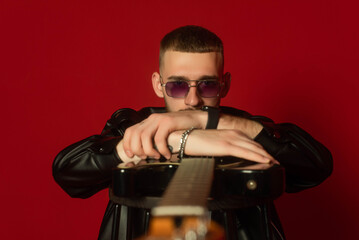 guitarist showing his instrument to the camera, perspective view. Isolated on a red background