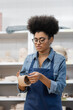 © LIGHTFIELD STUDIOS - curly african american woman with manicure and curly hair modeling clay cup in pottery workshop.