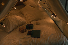 Gifts On Camping Tent Bed Decorated With Christmas Lights. Kid's Bedroom. Winter Holidays. Evening Atmosphere.