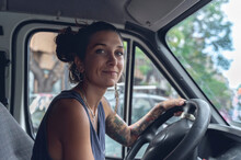 Young Woman, With Tattoos And Piercings, Driving A Van, Looks At The Room With Satisfied Expression.