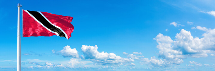 Wall Mural - Trinidad and Tobago, flag waving on a blue sky in beautiful clouds - Horizontal banner