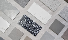 Top View Interior Mood Board. Material Samples Palette Contains Various Type, Texture And Color Of Artificial Stones, Marbles, Grainy Stone Tiles, Quartzs Placed On Grey Travertine Background.