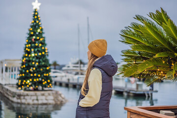 Wall Mural - Woman on the background of the Christmas tree. Christmas in the port. Montenegro, Porto Montenegro