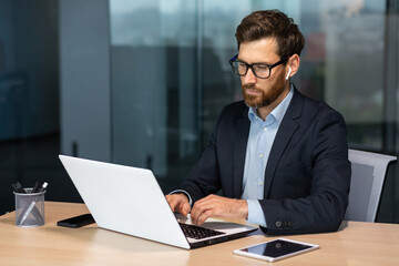 mature serious businessman working inside modern office building, senior boss in business suit typin