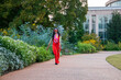 an African American woman wearing an orange jumpsuit skipping along a footpath the garden surrounded by colorful flowers and lush green trees at Atlanta Botanical Garden in Atlanta Georgia USA