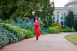 an African American woman wearing an orange jumpsuit skipping along a footpath the garden surrounded by colorful flowers and lush green trees at Atlanta Botanical Garden in Atlanta Georgia USA