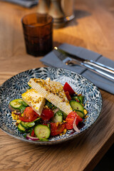 Canvas Print - Greek salad in a restaurant on a colored plate