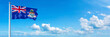 Cayman Islands flag waving on a blue sky in beautiful clouds - Horizontal banner