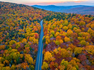 Canvas Print - Aerial view of road in colorful autumn mountain forest during sunset