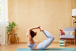 © ALTO IMAGES/Stocksy - Woman doing Padangushtha Dhanurasana A posture