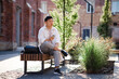 © Oleksii Syrotkin/Stocksy - Man sitting on bench with mobile phone