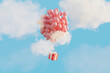 © Pixel Stories/Stocksy - Red gift floating in sky attached to red balloons