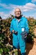 © Ezequiel Giménez/Stocksy - Positive senior farmer with grapes on farm