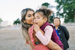 © Serena Burroughs/Stocksy - Mother and daughter hugging at the beach with the grandma nearby