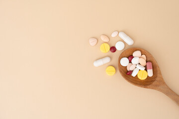 many colorful drug medicines or pill on wood spoon with yellow table, healthy and medicine concept