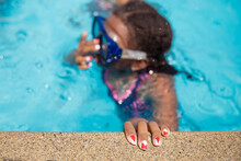 Child With Hand On The Concrete Edge Of A Pool