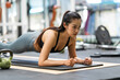 © crizzystudio - Asian woman doing to 'plank'. exercise concept.Fitness Asian doing yoga in a gym.Young woman doing pilates, working on abdominal muscles, and exercising to improve core muscle strength in the gym...