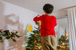 © ByLorena/Stocksy - Boy decorating Christmas tree at home