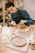 © Duet Postscriptum/Stocksy - A young woman sculpts a mug at a work table